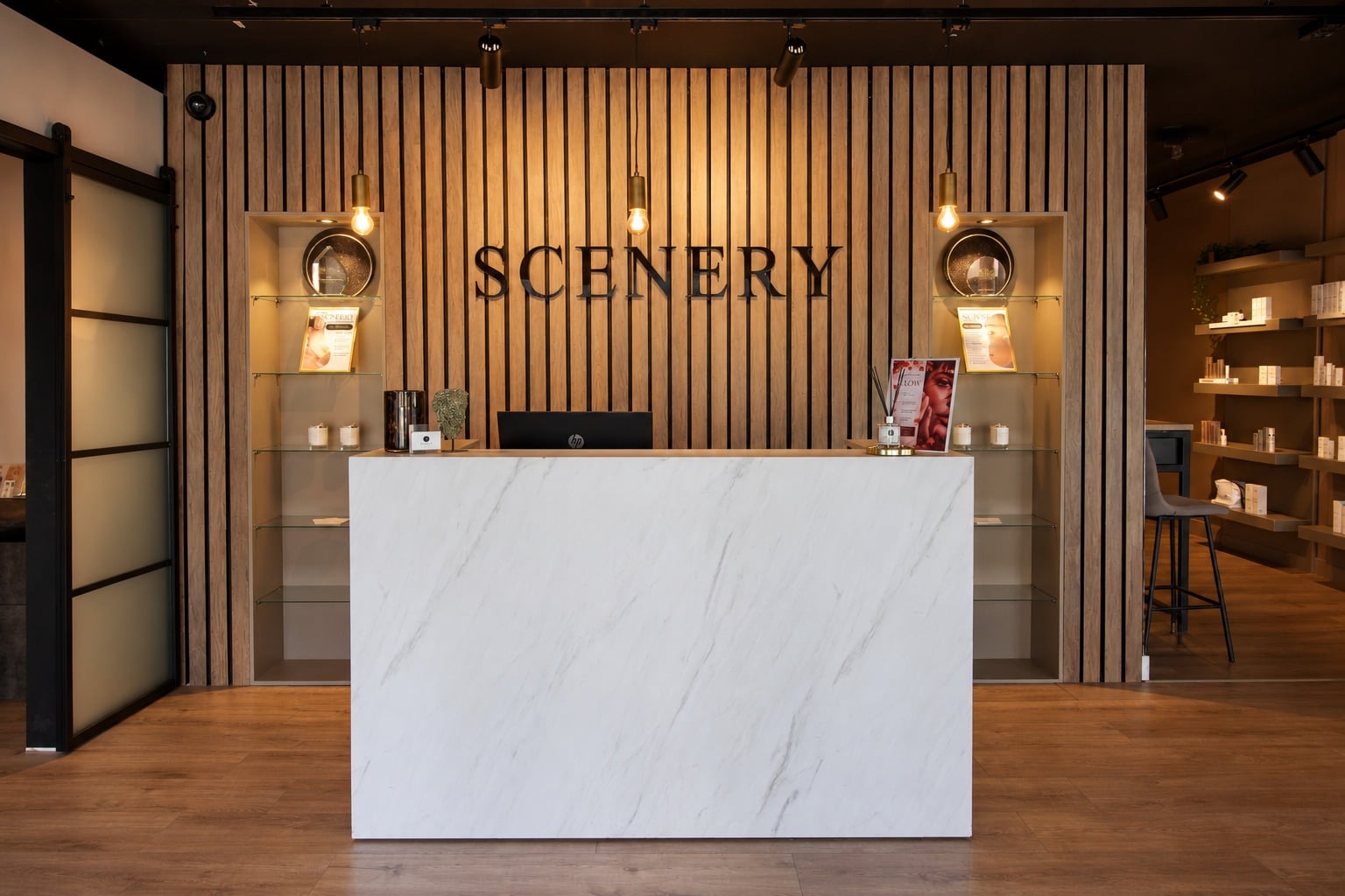 Balie van SCENERY Beauty voor een houten lamellenwand met het logo
