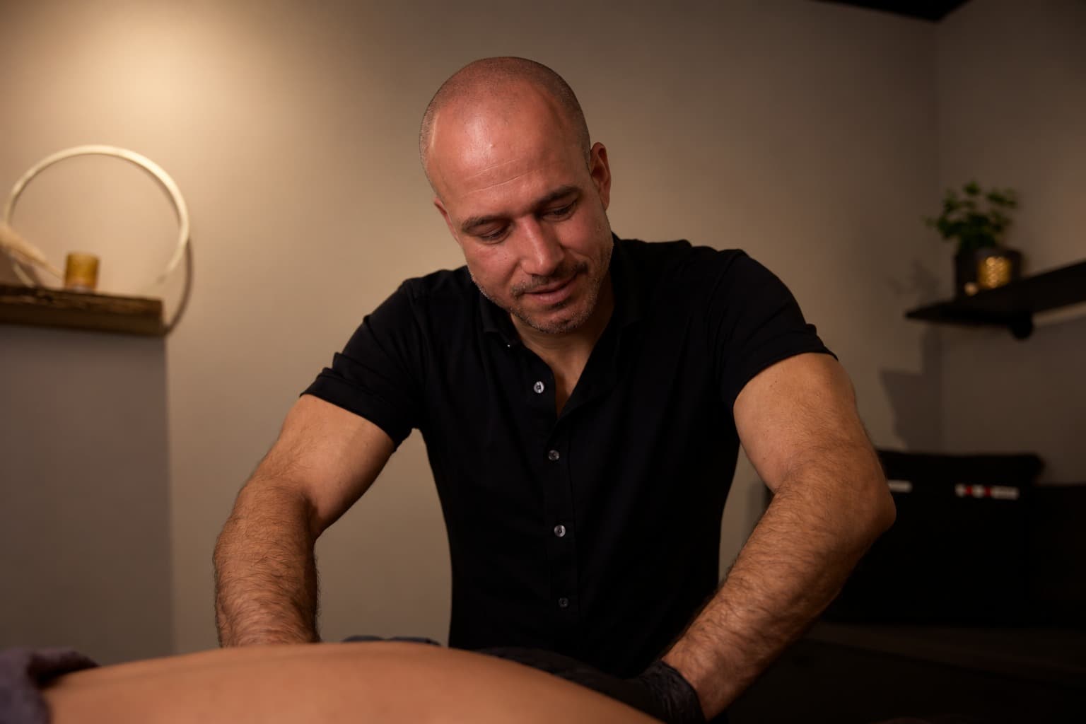Jeff Verbeek kijkt glimlachend omlaag terwijl hij werkt, in warm licht