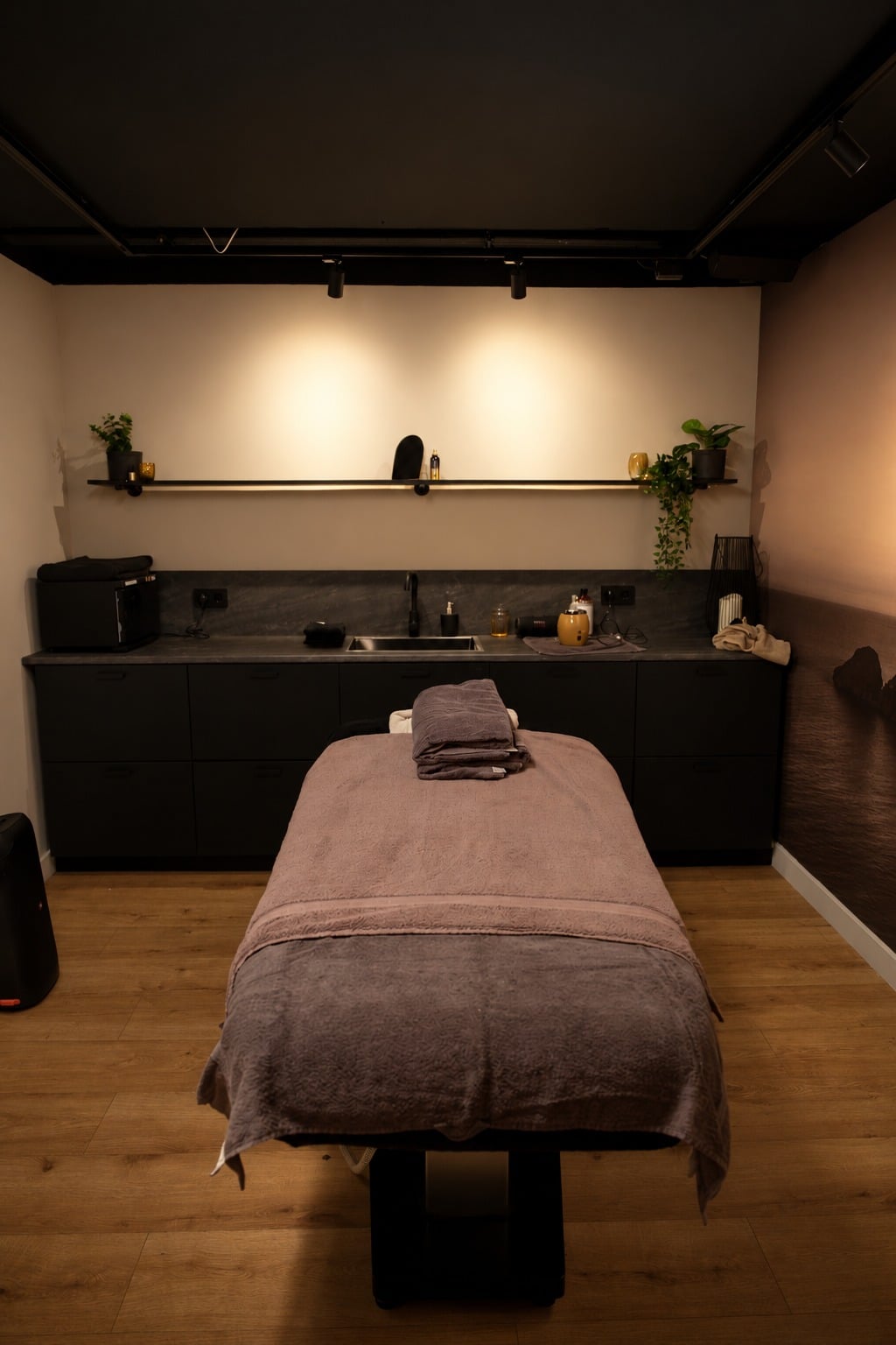 De lege behandelruimte: massagetafel met opgevouwen handdoeken onder warme wandspots